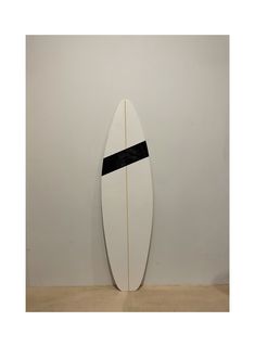 a white surfboard leaning against a wall with a black strip on it's side