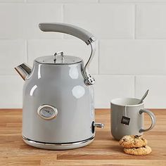 a tea kettle next to a cookie on a wooden table