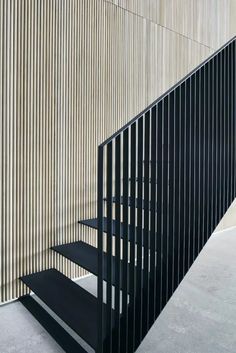 a set of black stairs next to a wall with vertical slats on the side