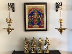 brass figurines are lined up on a shelf in front of a framed painting