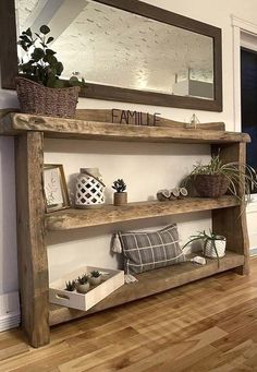 a wooden shelf sitting on top of a hard wood floor next to a mirror and potted plants