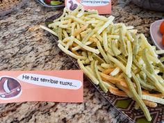 french fries and carrots on a table with some paper signs that say he has terrible usts