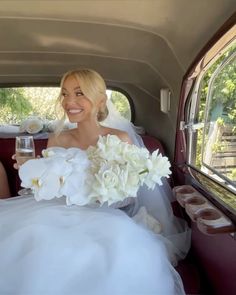 a bride and groom sitting in the back of a car with flowers on their lap