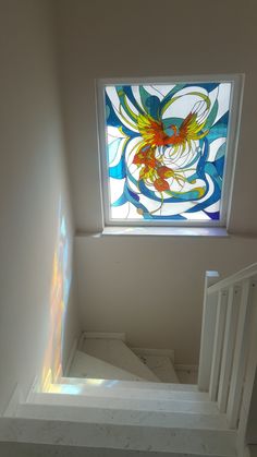 an empty stairwell with stained glass window above it