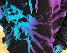 a person wearing a black and purple hoodie with blue paint splatters on it