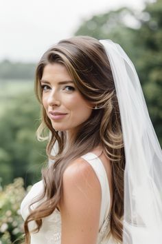 a woman in a wedding dress with a veil on her head looking at the camera