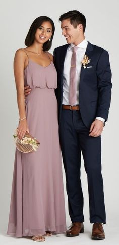 a man and woman in formal wear standing next to each other smiling at the camera