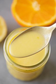 a spoon full of liquid next to an orange