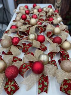 a table topped with red and gold christmas ornaments on top of white cloth covered tables