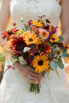 a bride holding a bouquet of sunflowers and other flowers