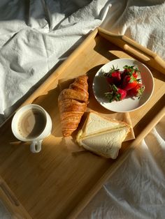 a tray with bread, strawberries and a cup of coffee sitting on top of it