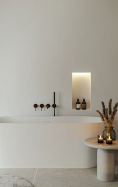 a white bathroom with candles on the counter and two vases in front of it