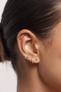 a woman's ear with three different piercings