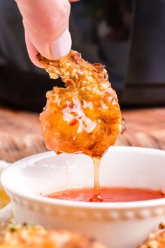 a person dipping some food into a small white bowl with sauce in front of them