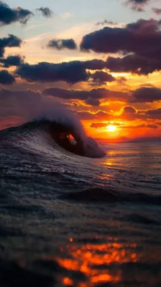 the sun is setting behind an ocean wave