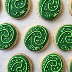 some cookies with green frosting are arranged on a white tablecloth and decorated in the shape of spirals