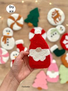 someone holding up a knitted santa clause ornament in front of christmas decorations