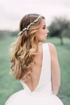 the back of a woman's head wearing a white wedding dress with flowers in her hair