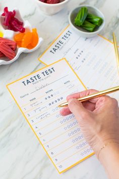 a person writing on a paper with gummy bears in bowls and other candies