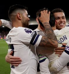 three soccer players are hugging each other in the middle of a group on a field