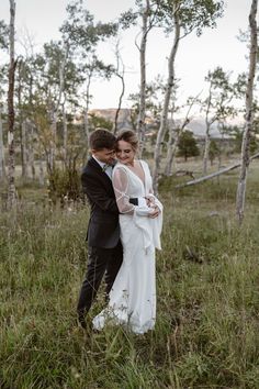 a bride and groom standing in the grass