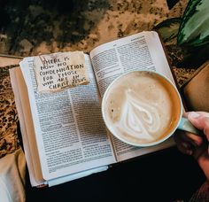 a cup of coffee sitting on top of an open book