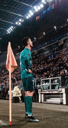 a soccer player standing on the field in front of an audience at a sporting event