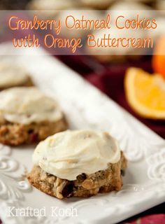 cookies with orange buttercream are sitting on a white plate next to an orange slice