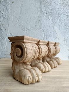 a close up of a wooden object on a table with a wall in the background