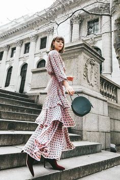 a woman in a polka dot dress is walking down the steps with a black pan