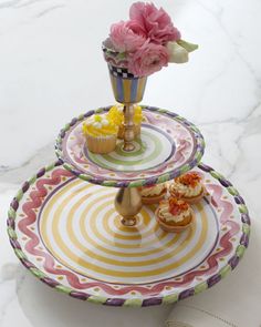 three tiered trays with flowers and cupcakes on them sitting on a marble surface