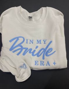 a white shirt that says in my bride era with blue writing on the front and back