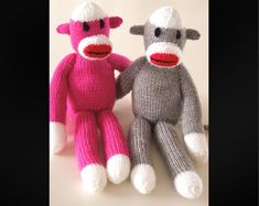 two knitted sock monkeys sitting next to each other on a white surface with black background