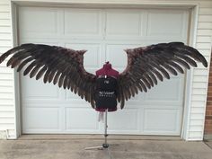 a mannequin dressed as an eagle with wings spread out in front of a garage door