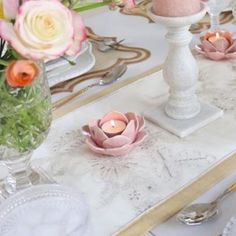 a table topped with plates and vases filled with pink flowers on top of it