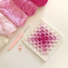 a crochet square with yarn and knitting needles next to it