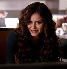 a smiling woman sitting at a table in a restaurant