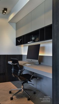 an office desk with a computer on top of it in front of a book shelf