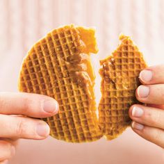 two hands holding up a waffle with peanut butter on it