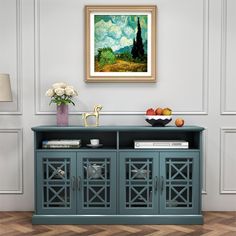 a painting hanging on the wall next to a blue cabinet with fruit and flowers in it