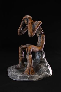 a sculpture of a person sitting on a rock with their hands behind their head and arms in the air