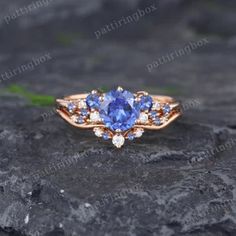 a tan gold ring with blue sapphires and white diamonds on the side, sitting on top of a rock