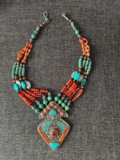 This stunning Middle Eastern handmade necklace is from Oman. It's intricate design features what I believe to be of low silver with ornamentation and semi-precious stones. The multitude of colorful beads make this eye-catching necklace a statement piece. The workmanship is typical of tribal silversmithing.  It is in very good condition. The date is unknown, possibly from mid-century. Measures approximately 19" long from one end of the clasp to the other. Artisan Beaded Turquoise Necklace For Festivals, Silver Bohemian Turquoise Necklace For Festivals, Traditional Turquoise Pendant Necklace With Polished Beads, Bohemian Silver Turquoise Necklace For Festivals, Traditional Beaded Turquoise Pendant Necklace, Silver Beaded Turquoise Necklace For Festivals, Traditional Silver Beaded Necklace, Traditional Turquoise Necklace For Festivals With Silver Accents, Traditional Beaded Silver Turquoise Necklace