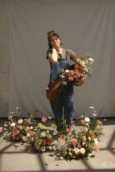 a woman standing in front of flowers with her hand on her face