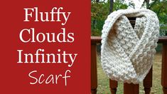 a white scarf sitting on top of a wooden rail next to a red sign that says fluffy clouds infinity scarf