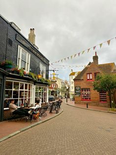 people are sitting at tables in the middle of an empty street with bunting and flags