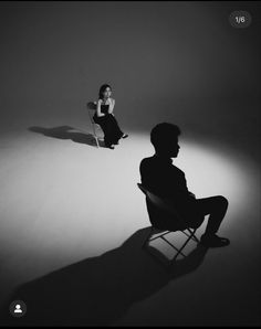 a man sitting in a chair next to a woman with a skateboard on her feet