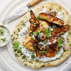 a flatbread pizza topped with grilled chicken and herbs next to a small bowl of ranch dressing