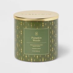 pumpkin woods candle tin in green with gold dots on the lid and inside, sitting on a white surface