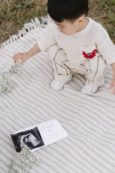 a little boy sitting on top of a blanket next to a book